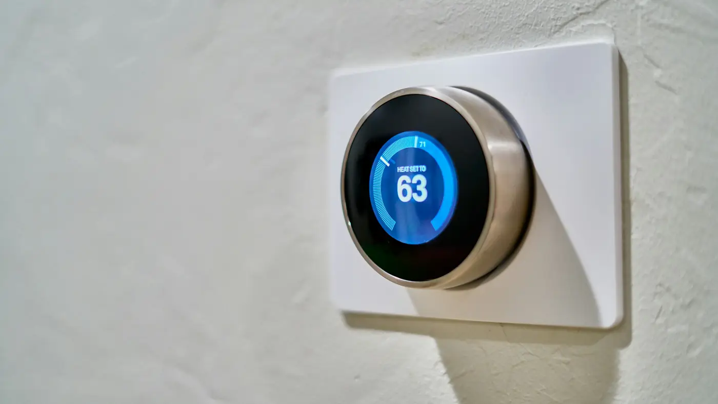 A round smart thermostat on a white wall