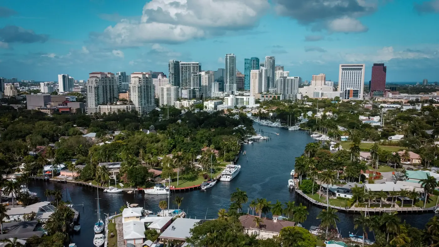 Canals with homes, boats and palm trees below the Fort Lauderdale skyline