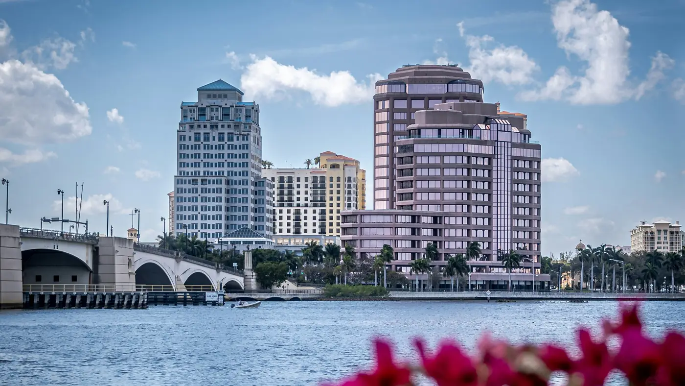 Edificios y puente de West Palm Beach junto al agua, tras unas buganvilias